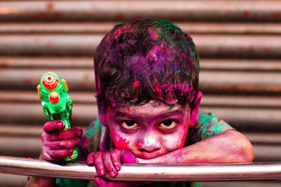 Portrait of boy covered with colors holding holi gun