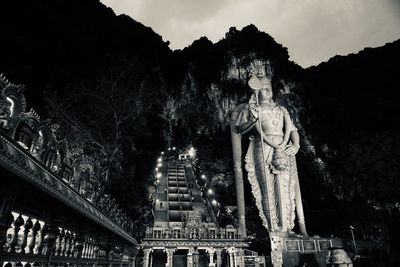 Statue by historic building against trees and temple