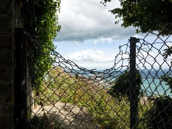 Close-up of barbed wire fence on field against sky