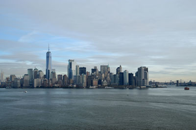 Sea and buildings in city against sky