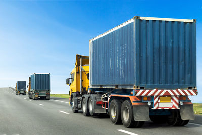 Vehicles on road against blue sky