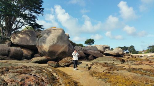 Man photographing through mobile phone while standing on landscape against sky