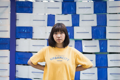 Portrait of young woman standing in shelf