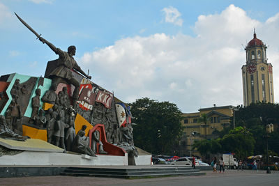 Statue by building in city against sky