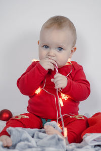 Portrait of cute baby boy sitting on bed at home