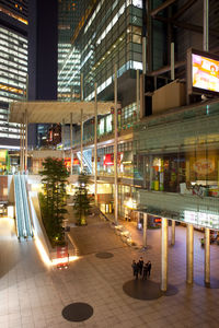 Illuminated street by buildings in city at night