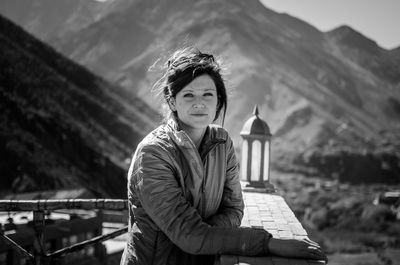 Portrait of woman standing by railing against mountains