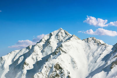 Scenic view of snowcapped mountains against blue sky