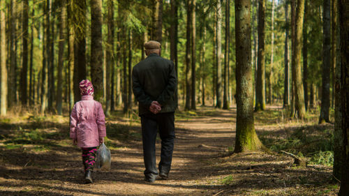 Rear view of man and woman walking in forest