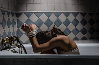 Rear view of woman sitting in bathroom