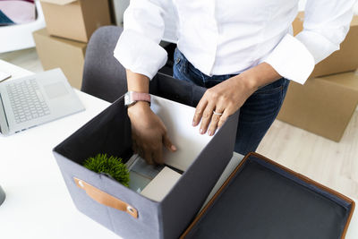 Hands of businesswoman packing boxes before office relocation