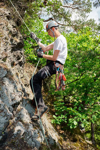 Full length of boy climbing on rock in forest