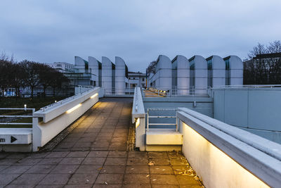 Empty footpath in city against sky