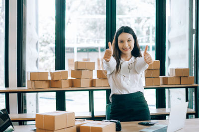 Portrait of a smiling young woman standing against window