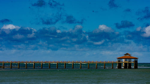 Pier over sea against blue sky