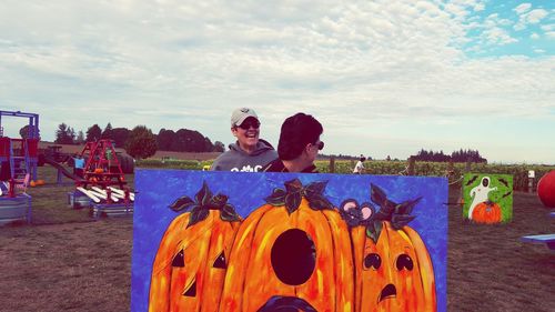 People standing by pumpkin art on field