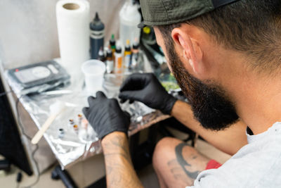 Side view of tattoo artist holding bottle in workshop