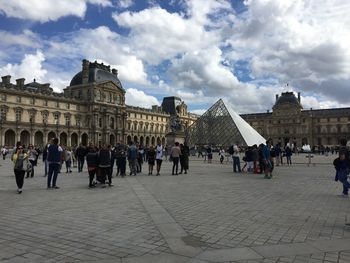 Tourists in front of historical building against sky