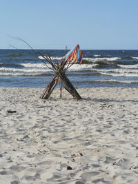 Fabric hanging on sticks on shore at beach against clear sky