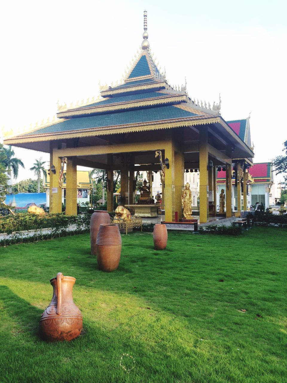 grass, architecture, built structure, building exterior, statue, sculpture, art, temple - building, art and craft, religion, human representation, lawn, clear sky, creativity, history, spirituality, sky, place of worship, animal representation