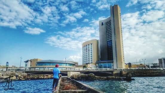 architecture, building exterior, built structure, water, sky, cloud - sky, city, blue, river, cloud, waterfront, cloudy, modern, skyscraper, railing, day, city life, tower