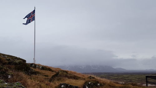 Low angle view of flag on mountain against sky