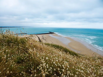 Scenic view of beach against cloudy sky