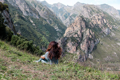 Rear view of woman sitting against mountains