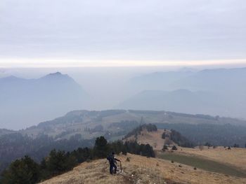 Man riding horse on mountain against sky