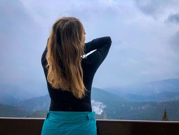 Rear view of woman looking at mountains against sky