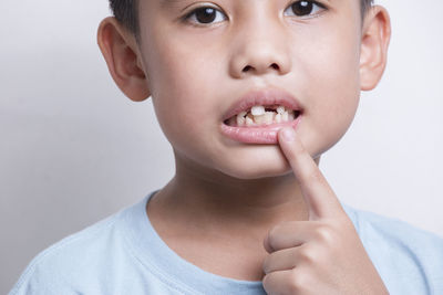 Asian boy's face looking at the tooth and showing teeth behind on white background first teeth