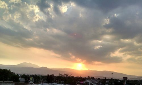 Scenic view of mountains against cloudy sky at sunset