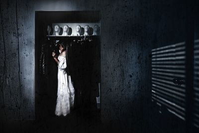 Side view of woman standing in dark room