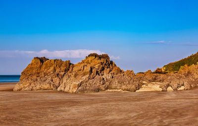 Rock formations on beach against blue sky