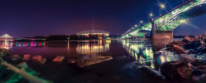 Illuminated bridge over river at night