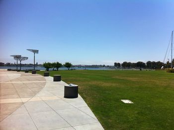 Empty footpath against clear blue sky