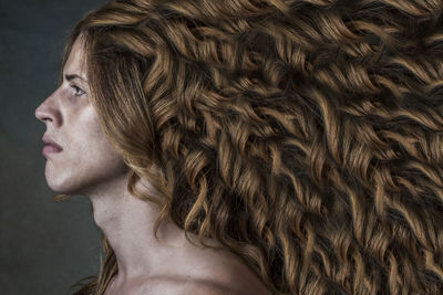 Close-up of man with wavy hair against gray background