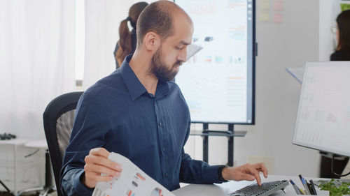 Side view of businessman using laptop at office