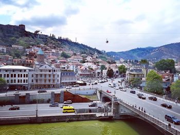 Bridge over river by buildings in city against sky