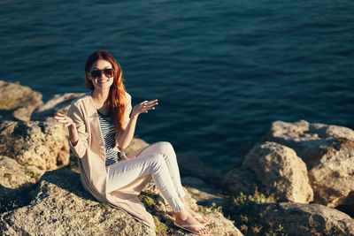 Man sitting on rock by sea