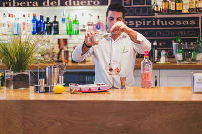 Young bartender preparing drink at counter