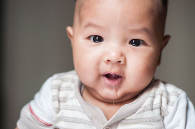 Portrait of cute boy dripping saliva against gray background