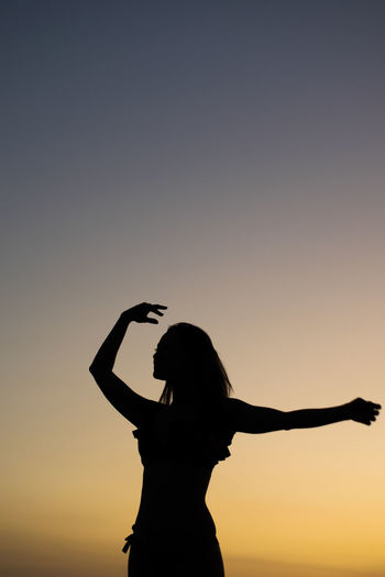 Silhouette woman dancing against sky during sunset