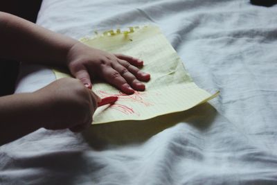 High angle view of child drawing on paper at bed