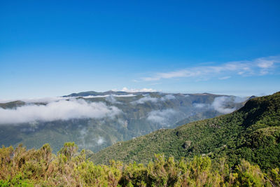 Scenic view of land and mountains against blue sky