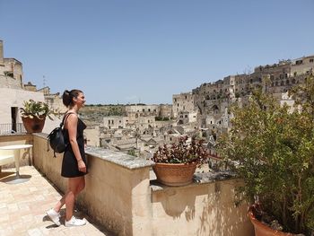 Woman standing by plants against clear sky