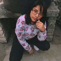 High angle portrait of woman crouching against fireplace