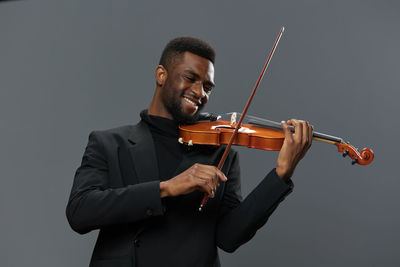 Midsection of man playing violin against white background
