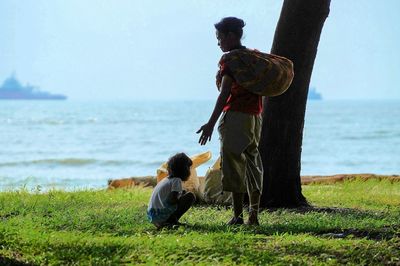 Rear view of men standing at beach