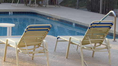 Empty chairs by pool